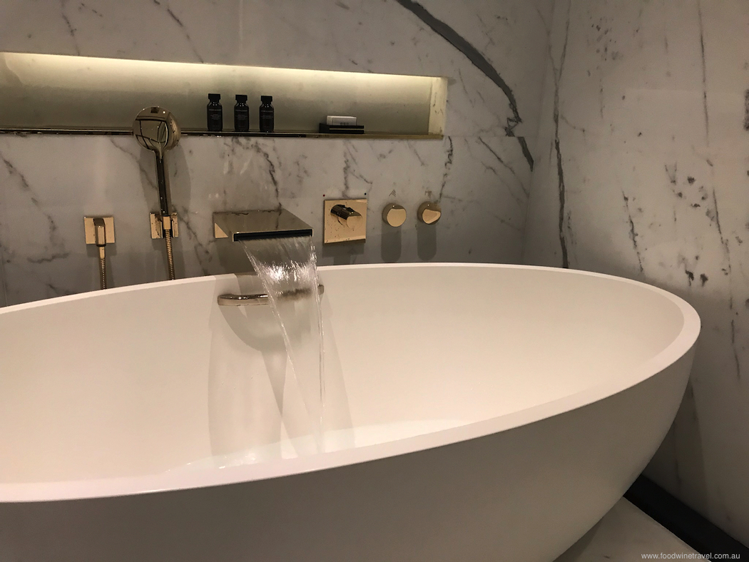 The sumptuous bathroom with marble walls and gold fittings.