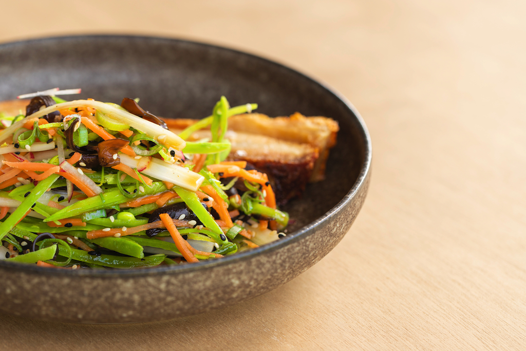 Roast pork belly with a pickled salad of snow peas, carrot, fungi and orange dressing.