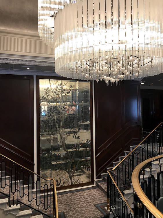 A dramatic glass wall rises up behind the Grand Staircase.