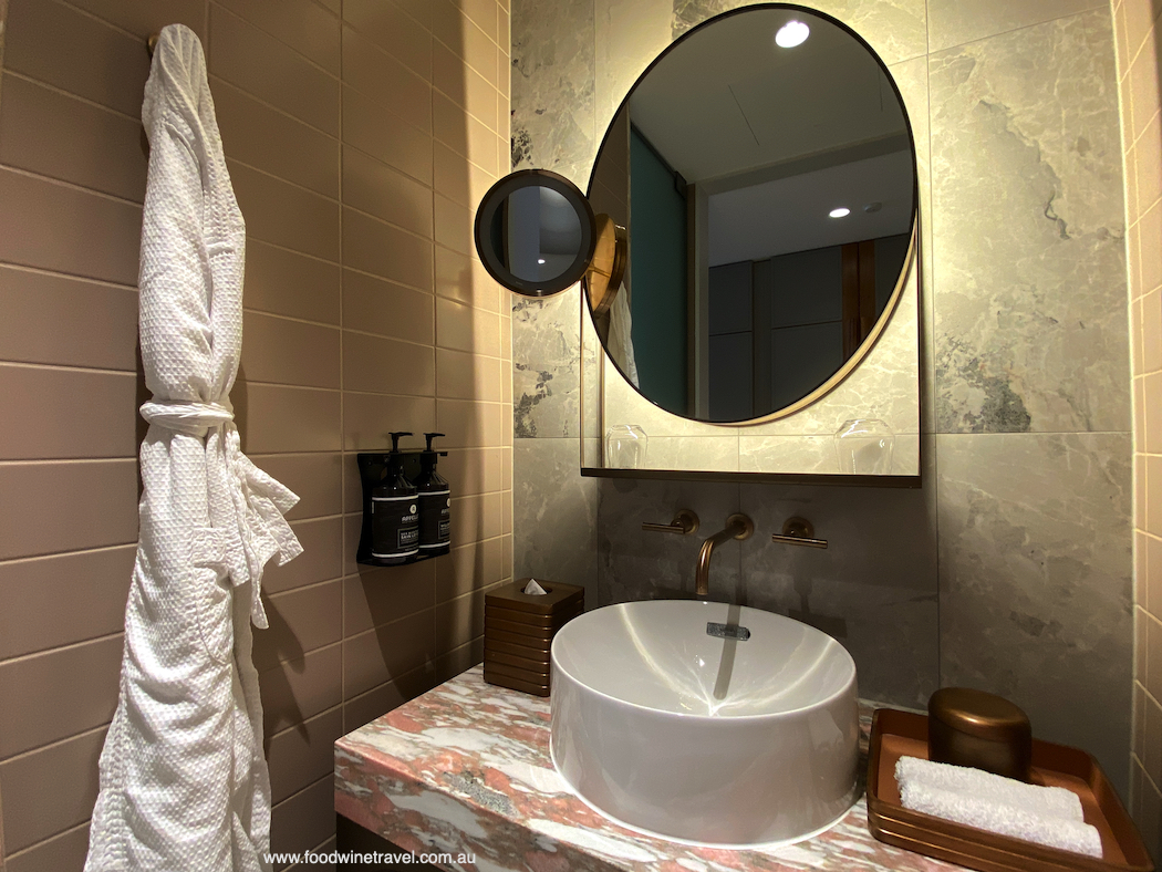 Pink and grey marble tones, and brass fittings, in the bathroom.