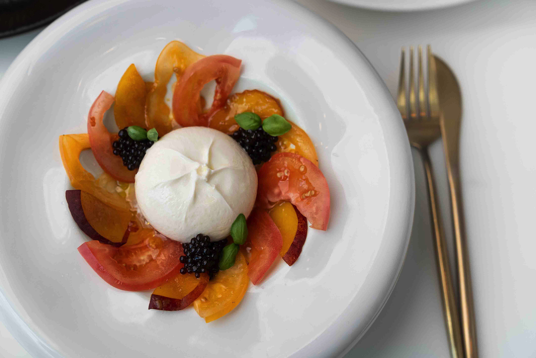 Burrata with heirloom tomatoes, garnished with greens from the restaurant's vertical garden.