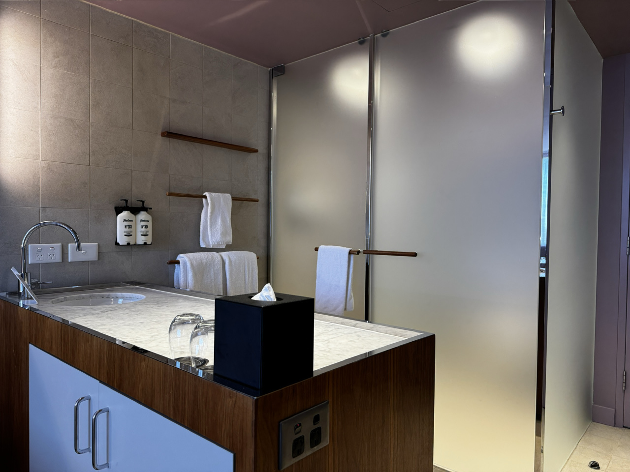 A bathroom bench divides the shower and toilet cubicles from the rest of the room.